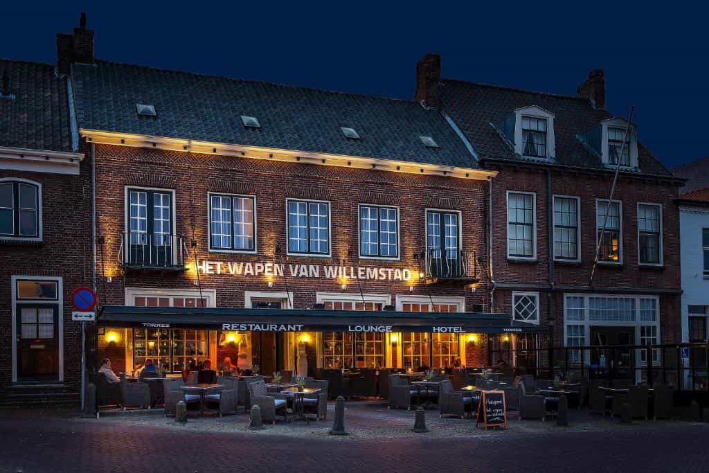 Restaurant and hotel "Het Wapen van Willemstad" illuminated at dusk with outdoor seating