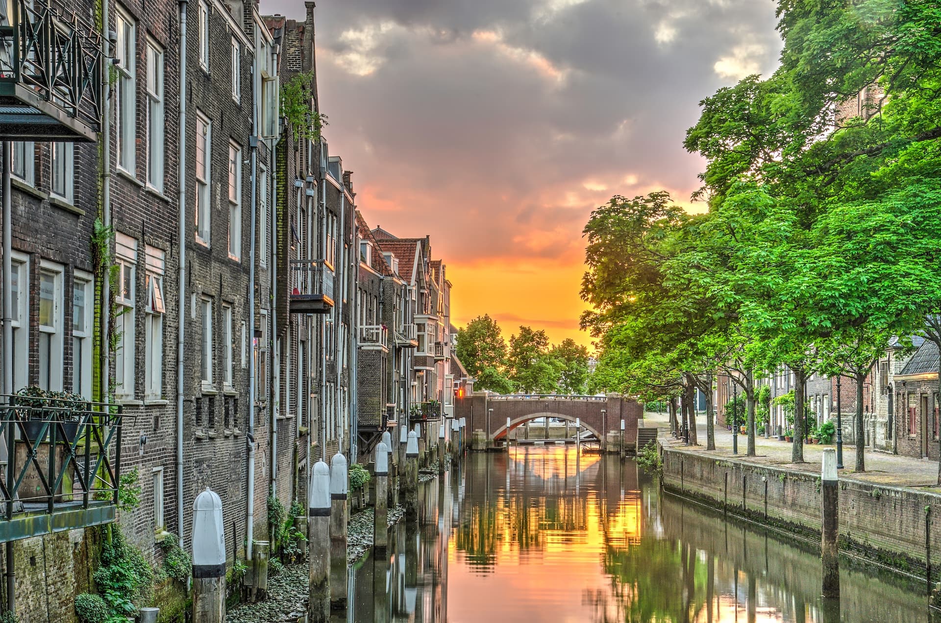 Canal with historic brick buildings and bridge reflecting sunset in Dordrecht