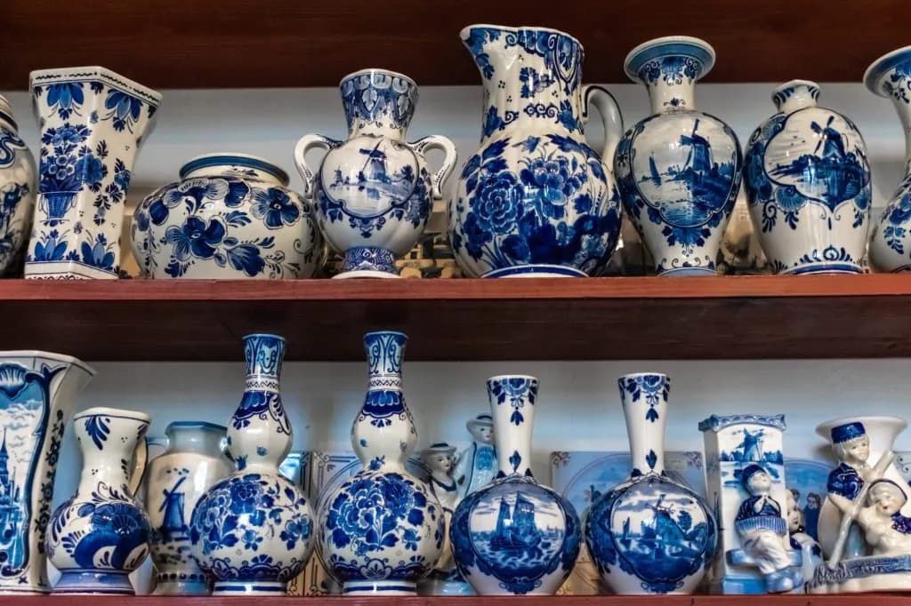 Blue and white Delftware pottery, including vases and figurines, displayed on wooden shelves