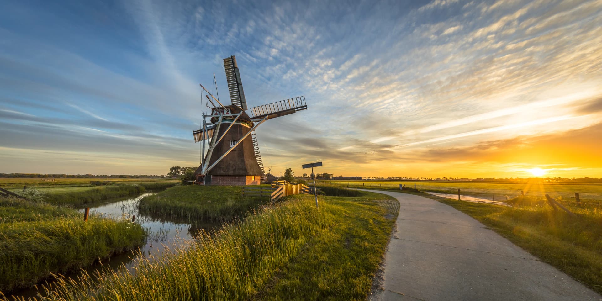 Wooden windmill with cycling track at sunset