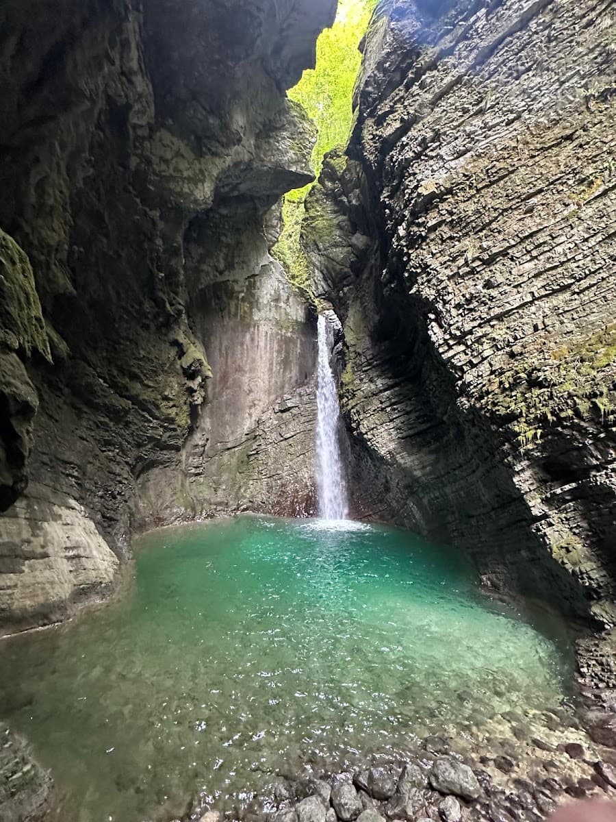 Waterfall flowing into a turquoise pool enclosed by rocky canyon walls