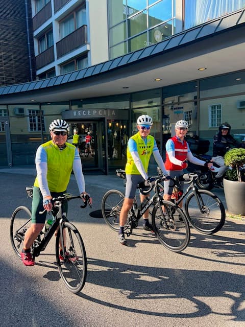 Cyclists in cycling gear with bicycles in front of hotel entrance with RESTEPCIJA sign